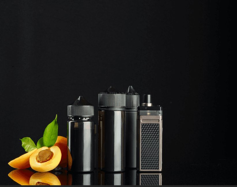 Vape juice bottles and pod device with apricot fruit on black background