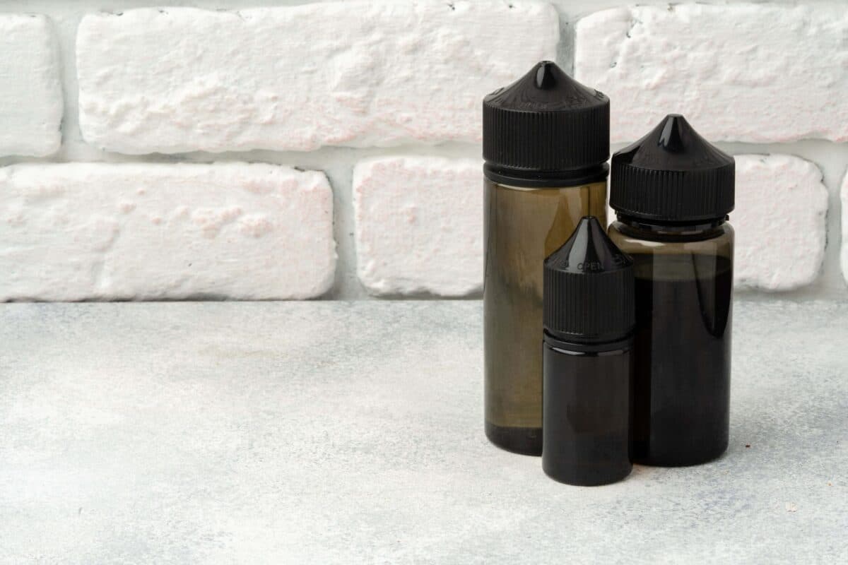 Properly stored vape juice bottles in dark containers on a light background