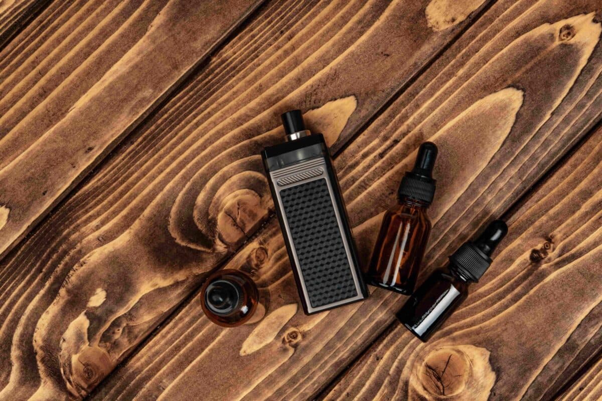 Vape device and e-liquid bottles placed on a rustic wooden table, showcasing nicotine salts for a smoother vaping experience
