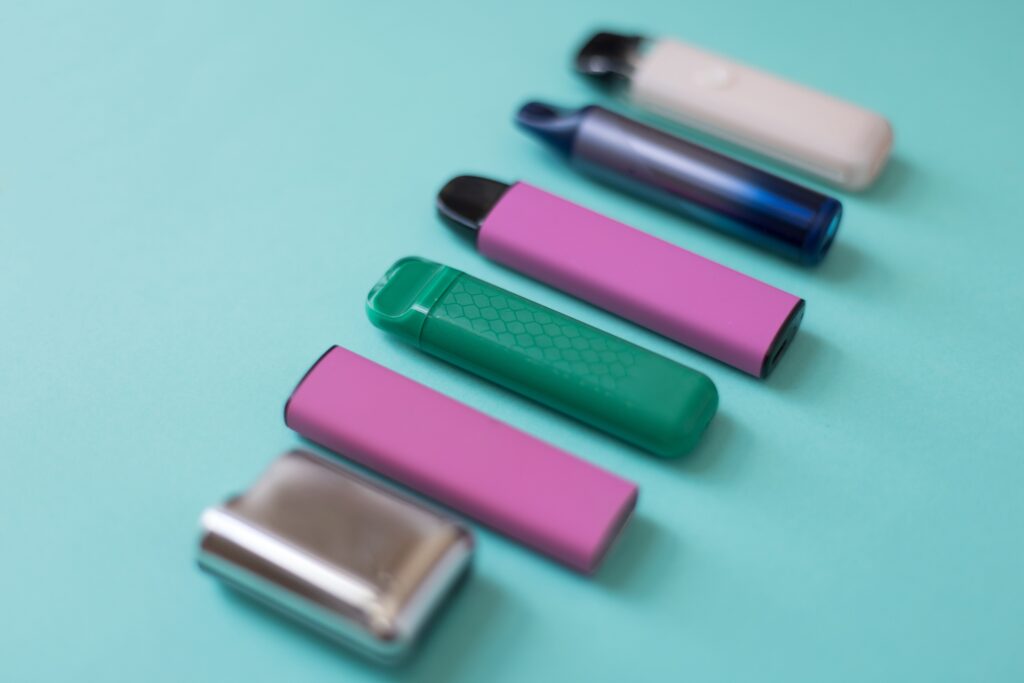 Colorful Disposable Vape Devices: Convenience and Single-Use Design Assorted colorful disposable vapes on a green background, highlighting their convenience and single-use design.