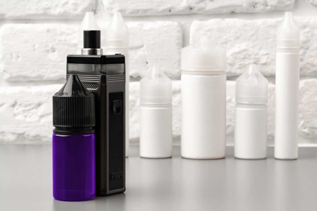 Vape Juice Bottle and Device: Essential Ingredients for a Customizable Vaping Experience Vape juice bottle next to vaping device, showcasing e-liquid bottle types used for vaping.